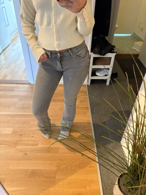 Grå raka jeans med hög midja - Säljer ett par grå jeans med rak passform och hög midja. Jeansen har klassiska fem fickor och bälteshällor. Materialet är denim med en lätt stretch för extra komfort. Perfekta till en avslappnad och trendig look.