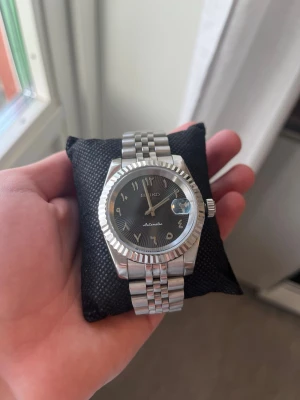 Seiko automatisk klocka i silver - Modifierad klocka med NH35A verk (automatisk). Safir glas dvs skrapas ej. Seiko Mod med arabiska siffror. Box ingår dock bra att veta att det ej är orginal box. 39mm. Extra länkar ingår för att kunna justera storleken. Sökord: #seiko #klocka #kläder #herrkläder #damkläder #dam #herr #nike #adidas #tröja #tröjor #byxa #byxor #sport #tissot #smycke #smycken #guld #silver 