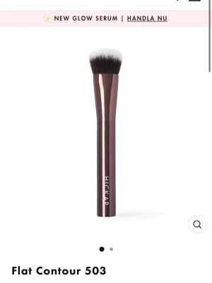 Flat Contour 503 sminkborste Hickap - Flat Contour 503 från Hickap är en sminkborste med platt, tät borst i syntetiskt material. Handtaget är metallicbrunt och borsten har svart till vit ombre-effekt. Perfekt för contouring och detaljerad applicering av makeup.