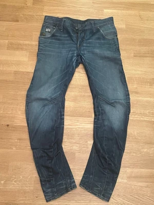  G-Star jeans - Säljer ett par mörkblå jeans från G-Star RAW med snygga slitningar. De är Tapered fit. De är knappt använda men används ej. Hör av er vid fler frågor