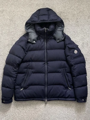 Moncler Montgenevre Navy - Montgenevre Flannel Down Jacket Navy, säljes i bra skick | Sparsamt använd | Storlek 5 | Hör av er vid eventuella frågor eller funderingar!