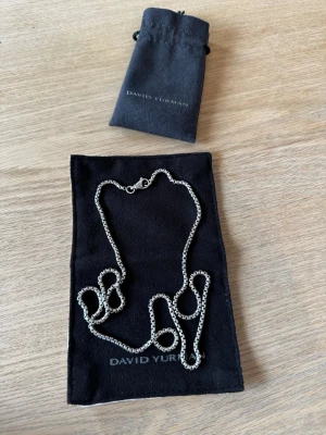 David Yurman - Box Chain - Säljer ett stilrent silverhalsband från David Yurman. Halsbandet kommer med original svart tygpåse och är perfekt för dig som gillar klassiska accessoarer med exklusiv känsla. Box chain 2,7mm & 26inch (66cm) nypris är 325€ 