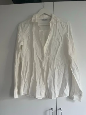 Vit långärmad skjorta  - Säljer en klassisk vit skjorta  med lång ärm och knappar framtill. Skjortan har en tidlös design med krage och är tillverkad i ett lätt bomullsmaterial. 