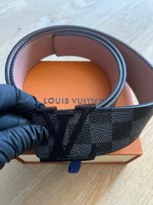  svart bälte med spänne - Snyggt svart bälte med klassiskt rutigt mönster och stort spänne i svart metall. Bältet har en exklusiv känsla, perfekt för att lyfta vilken outfit som helst. OBS: bara bältet tillkommer.