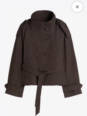 Kort brun trenchcoat med bälte - Brun kort trenchcoat från bershka med knyt i midjan. Jackan är använd endast en gång!