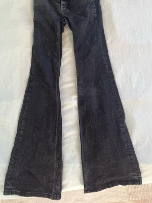 Svarta/gråa bootcut jeans Bell från Lager157 - Säljer ett par svarta/gråa bootcut jeans med utsvängda ben och klassisk femficksdesign. Jeansen har en snygg tvättad look och är tillverkade i denim. Perfekta för dig som gillar retrostil och vill ha ett par jeans som sticker ut.