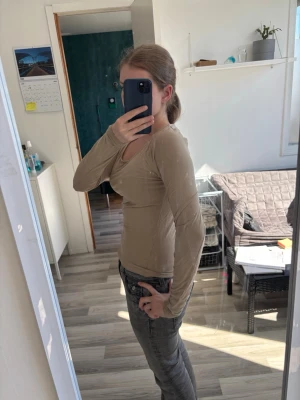 Beige långärmad topp med rund hals - Snygg beige långärmad topp med rund halsringning och tight passform. Perfekt att styla med jeans eller kjol för en clean och enkel look. Mjuk och stretchig känsla i materialet.