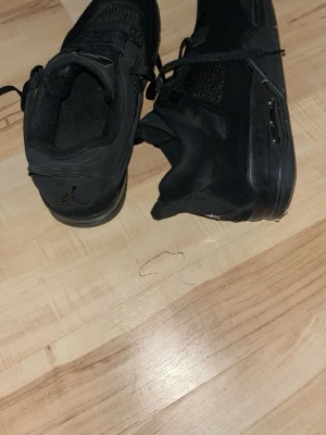 Svarta Air Jordan 4 sneakers - Säljer ett par helsvarta Air Jordan 4 sneakers med klassisk siluett och meshdetaljer på sidorna. Skorna har synlig Air-enhet i sulan och Jumpman-logga på plösen och hälen. Perfekta för dig som gillar streetwear och sportig stil. Har andvänt dom 3-4gånger när jag var utomlands för ungefär 4 månader sedan