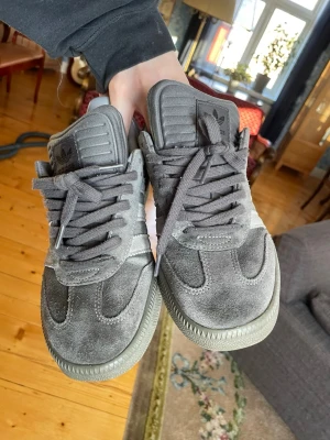Grå Adidas Sambas i mocka - Jag säljer ett par grå Adidas Samba i mocka. Skorna ger lite retrovibe o är i bra skick. Perfekta för dig som gillar cool streetwear, strl 42 men passar typ mer som 40/41. Skorna är typ chunky eller vad man säger                                          Kom med prisförslag vetja 🙂🙂
