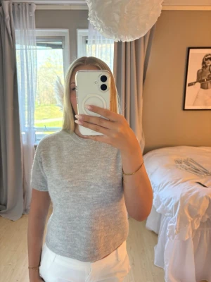Grå stickad t-shirt med kort ärm - Säljer en stilren grå stickad t-shirt med korta ärmar och rund hals. 