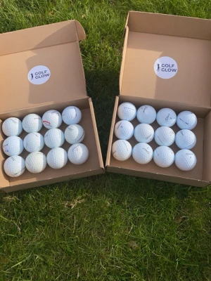 PRO V1 A/B-Klass och PRO V1 C/D-Klass  - Säljer flera vita golfbollar i två kartonger från Golf Glow. Bollarna är av märket Titleist och har klassisk rund form med dimple-mönster. Perfekt för dig som vill fylla på golfutrustningen med kvalitetsbollar.