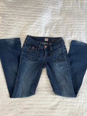 Blå bootcut jeans från ONLY - Blå vintage bootcut jeans från ONLY, (jätte) gammal modell, Ebba. Jeansen har låg midja, klassiska fem fickor och orangea sömmar.