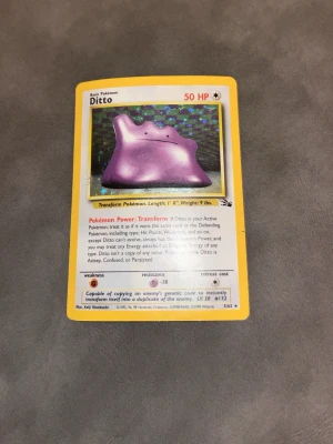 Pokémonkort Ditto Base Set Holo - Säljer ett original Pokémonkort av Ditto från Base Set, holografisk version. Kortet har gul ram, holografisk bakgrund och motiv av den lila Pokémon Ditto. Perfekt för samlare eller Pokémonfans som vill utöka sin samling.