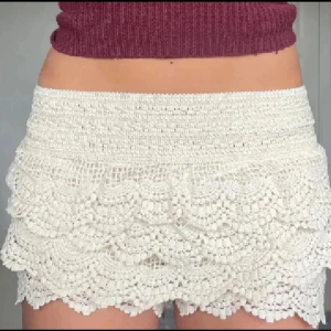 Beige virkade spets-shorts - Superfina beige shorts med virkade spetsvolanger och hög midja. De har en elastisk midja för skön passform och är perfekta för sommarens varma dagar. Ger en romantisk och bohemisk vibe till din outfit.