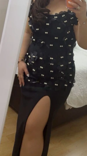 Svart långklänning med pärldetaljer - Svart långklänning med offshoulder-design och dekorativa pärlor samt blommiga applikationer över hela överdelen. Klänningen har en hög slits framtill och figurnära passform som ger en elegant siluett. Perfekt för dig som vill sticka ut. Klänningen är endast använd i några timmar och är köpt för 799 men minns inte från vart. Vid intresse kan jag skicka fler bilder! Storlek 40/L men passar även 38/M