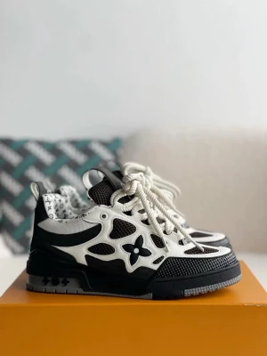 LV Skates - Snygga svartvita LV sneakers med ikoniska monogramdetaljer och LV-logga på plösen. Skorna har en chunky sula, meshpaneler och läderdetaljer. Insidan är fodrad med LV-mönster och de har vita och svarta skosnören. Perfekt för dig som gillar exklusiv streetwear. Snabb affär kan pris diskuteras. 