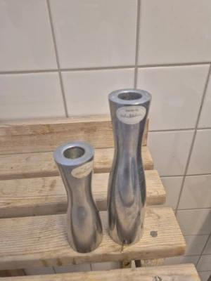 Designade aluminiumljusstakar - Två stilrena ljusstakar i blank aluminium, designade av Erik Höglund. De har en modern, avsmalnande form och är silverfärgade. Perfekta som snygga detaljer i hemmet och säljs som par.