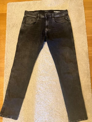 Svarta  jeans från Replay (NYA) - Säljer ett par svarta skinny jeans från Replay med klassisk femficksmodell och snygga slitningar. Jeansen har en smal passform och detaljer som Replay-logga på bakfickan och patch i midjan. Perfekta för en trendig och avslappnad stil. Storlek 33/32 använda 2 gånger i perfekt skick
