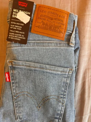 Levi's Mile High Super Skinny Jeans - Ljusa blå jeans från Levi's i modellen Mile High Super Skinny. Jeansen har extra hög midja och smal passform genom höft och lår. Klassisk femficksdesign, Levi's läderpatch bak och röd logotagg vid fickan. Tillverkade i stretchigt denim för en bekväm känsla. Köpte den helt ny från Levi's butik för 999 kr i USA