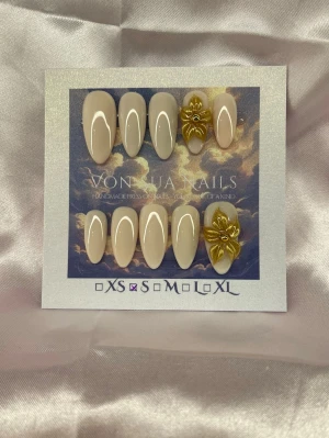 GoldieGlow (S);Medium Almond - Snygga handgjorda press-on naglar i nude färg med unika handgjorda 3D-blommor i guld. Medium lång andelformade och handgjorda för en exklusiv look. Perfekt för dig som vill ha något extra och trendigt på naglarna.