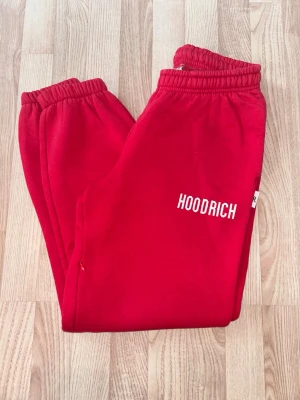 Röda mjukisbyxor från Hoodrich - Snygga röda mjukisbyxor från Hoodrich med vit logga på vänster ben. Byxorna har resår i midjan med snöre, muddar vid bensluten och sidofickor.  Jag är 168 och enligt mig är de lite för korta på mig. Inte använt mycket alls men det mjuka i byxorna är inte lika mjukt längre pga tvätt. Säljer hoodie också!