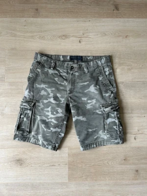 Gråa Camouflage Army Angelo Litrico Cargoshorts Storlek W36 - Mycket fina Angelo Litrico shorts i grå färg | Shortsen är i mycket bra skick och sparsamt använda. |  Äkta som allt annat jag säljer! ✅ |  Storlek: W36 | Skick: Mycket Bra Skick - har tyvärr en väldigt liten slitning (SE SISTA BILD) | Färg: Grå | Märke: Angelo Litrico | Modell: Shorts |   Hör gärna av dig vid frågor så svarar jag så fort jag kan! 😁 |  (SKU - 177)