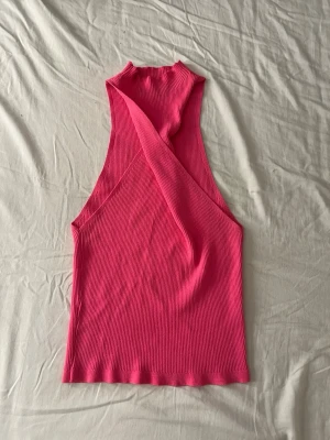 Rosa ribbad linnetopp från Gina Tricot - Säljer en snygg rosa ribbad linnetopp från Gina Tricot. Toppen har en croppad passform och ett coolt twistat axelbandslöst snitt framtill. Perfekt för dig som vill sticka ut med färg och stil i sommar!