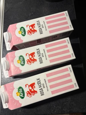 Arla Rosa Mjölk Jordgubb 1L - Tre förpackningar Arla Rosa Mjölk dryck med smak av jordgubb. Varje förpackning rymmer 1 liter och har en vit och rosa design med röd ko och grönt Arla-märke. 