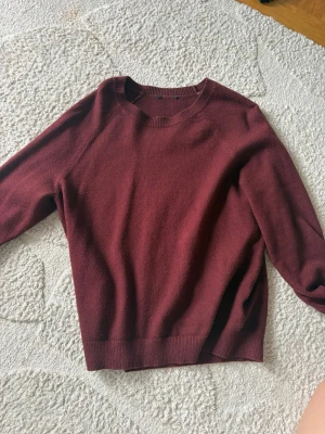 Mörkröd stickad tröja - En enkel och stilren mörkröd stickad tröja med rund halsringning och ribbade muddar vid ärmslut och nederkant. Perfekt för lager-på-lager och passar till det mesta. Materialet känns mjukt och mysigt. Original pris: 299kr 