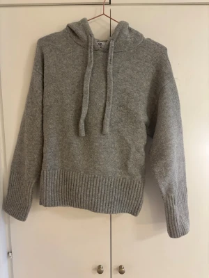 Grå stickad hoodie från Zara - Hoodien är lite nopprig på vissa ställen annars väldigt fint skick
