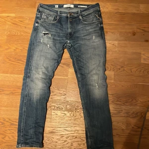 Replay anbass jeans 32/20 - Jättesnygga jeans i populäraste färgen. Byxorna är i slimfit men är du i vanliga fall runt 30 i midjan som jag så sitter de bra också. Jeansens skick är som på bilden med defekten på sista bilden men inget stort hål. Tveka inte att höra av er vid frågor. Säljer då jeansen då jag har graviterat mot annan passform.