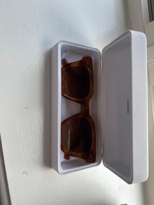 Bruna CHIMI solglasögon Havana - Snygga solglasögon från CHIMI i modellen Havana. De har en fyrkantig form och är i en brun transparent färg med mörka glas. Kommer i originalvitt fodral. Perfekta för dig som vill ha en stilren och trendig accessoar till sommaren.