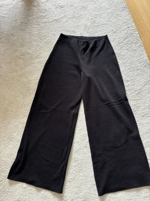 Svarta vida  byxor  - Säljer ett par svarta byxor med breda ben och hög midja. De är mjuka och stretchiga, perfekta för en chill och avslappnad stil. Passar lika bra till oversized tröjor som crop tops.