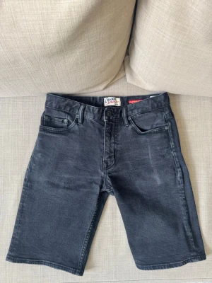 Svarta jeansshorts Crocker - Snygga svarta jeansshorts från Crocker med klassisk femficksdesign och knappgylf. Shortsen har en rak passform och bälteshällor i midjan. Perfekta för en avslappnad stil under varma dagar Frågor? skicka ett dm!