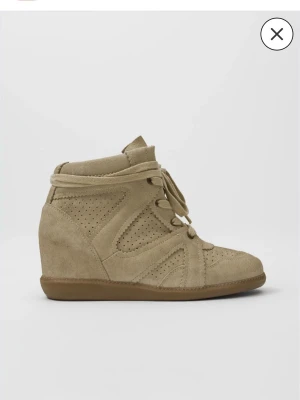 Beige kilklackade sneakers i mocka - Snygga beige sneakers med kilklack och perforerade detaljer. Skorna har snörning framtill och är gjorda i mjuk mocka med gummisula. Perfekt för dig som vill ha både stil och höjd i vardagen. Är från Nelly och endast testade. 