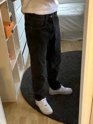 Svarta raka jeans från Pull&Bear - Snygga svarta jeans från Pull&Bear med rak passform och klassisk femficksdesign. Jeansen är tillverkade i denim och har en enkel, stilren look som passar till det mesta. Perfekta för dig som gillar en avslappnad men trendig stil.