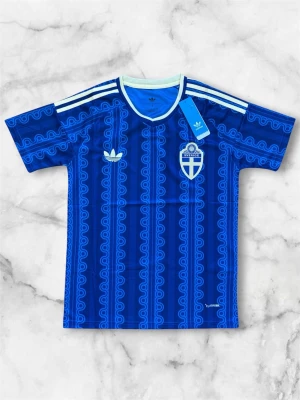 Blå Sverige fotbollströja Adidas - Säljer en blå fotbollströja från Adidas med Sveriges landslagsemblem på bröstet. Tröjan har ett unikt mönster i olika blå nyanser, vita Adidas-ränder på axlarna och rund halsringning med ljusblå kant. Perfekt för match eller träning.