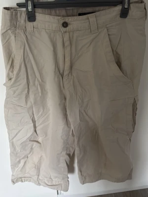 Beige cargoshorts från Dockers - Snygga beige cargoshorts från Dockers med klassisk passform och flera praktiska fickor. Tillverkade i bomull för en skön och luftig känsla. Perfekta för varma dagar och enkel att matcha med olika stilar.