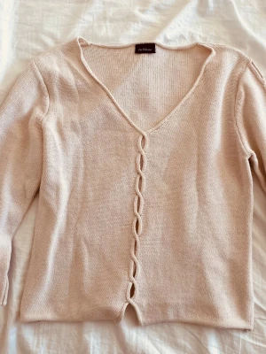 Beige kofta med twistad detalj - Säljer en ljusbeige kofta från In Wear med v-ringning och unik twistad detalj längs hela framsidan. Koftan har långa ärmar och är stickad i ett mjukt material som känns skönt mot huden. Perfekt för lager på lager och enkel att matcha. Skriv för fler bilder🥰