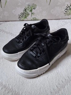 Svarta Nike sneakers med vit sula - Svarta Nike sneakers i läder med klassisk låg profil och vit chunky sula.
