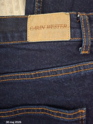 Mörkblå utsvängda jeans Carin Wester - Snygga mörkblå jeans från Carin Wester med utsvängda ben och klassiska kontrastsömmar. Jeansen har hög midja och är tillverkade i kraftigt denimtyg. Perfekta för dig som gillar en trendig och tidlös look.