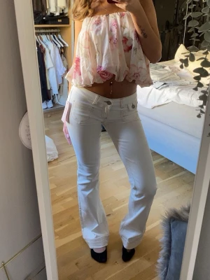 Vita bootcut jeans med låg midja - Säljer ett par helt oanvända bootcut jeans med låg midja och klassiska fem fickor. Jeansen har en snygg passform och är perfekta för en trendig och avslappnad look. Materialet är mjukt och stretchigt. 