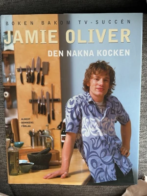 Jamie Oliver - Den nakna kocken - En inspirerande kokbok av Jamie Oliver med enkla och goda recept. Boken har ett färgstarkt omslag med Jamie i köket och innehåller många bilder på mat och matlagning. Perfekt för dig som vill laga mat utan krångel och med mycket smak.