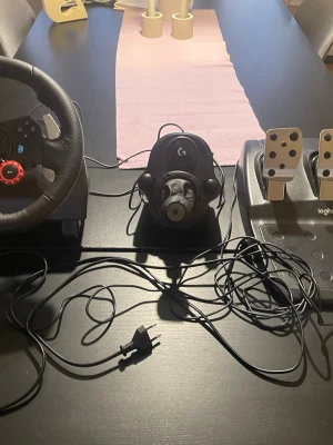 Logitech G29 ratt och pedaler PS4/ ps5/PC - Säljer en Logitech G29 racingratt med pedaler, kompatibel med PlayStation och PC. Ratten har svart konstläder, metallspakar och röda detaljer. Pedalerna är i metall och svart plast. Perfekt för racing- och bilspel för en realistisk spelupplevelse. Följer även med växelspak! Jag har haft den i ett år men har inte spelat så jätte mycket på de skriv gärna om frågor!