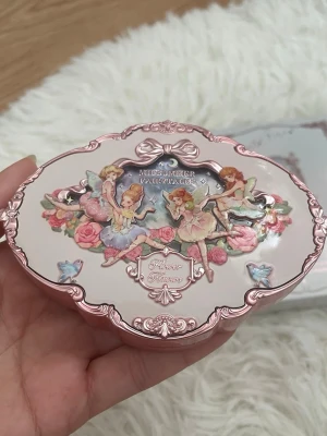 Midsummer Fairytales ögonskuggspalett - Magisk ögonskuggspalett från Flower Knows med sagoinspirerat etui i rosa metall och pastellfärger. Den som jag håller är för uppvisning bara. Jag ska skicka den nya i original förpackning.