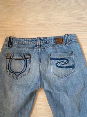Ljusblå bootcut jeans - Jättefina bootcut jeans, perfekta att ha till skolstart - passar till allt men fortfarande unika detaljer på bakfickorna. Midjemått är 36-37 cm, grenmåttet är 18 cm och innerbenslängden är 74 cm.