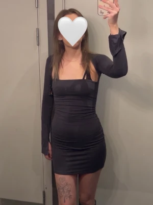 Mörkgrå långärmad klänning  - Snygg mörkgrå klänning med lång ärm och fyrkantig urringning. Modellen är tight och kort, vilket ger en modern och stilren look. Perfekt för dig som gillar minimalistisk stil och vill ha något enkelt men ändå trendigt. Nypris: 399. Använd enstaka gånger.