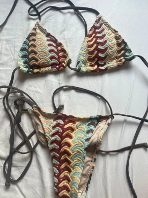 Missoni bikini  - Trendig virkad bikini med snörning i sidorna och över axlarna. Bikinin har ett vågigt mönster i ljusblått, vinrött, beige och brunt. Perfekt för sommarens strandhäng och poolpartyn.