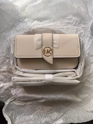 Beige handväska från Michael Kors - Snygg beige handväska från Michael Kors med guldfärgad MK-logga på locket. 