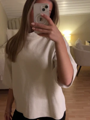 Vit oversized topp med trekvartsärm - Säljer en vit oversized topp med trekvartsärm och hög hals. Toppen har en enkel och clean look, perfekt att styla med jeans eller kjol. Materialet känns mjukt och lite tjockare, vilket ger en avslappnad vibe.